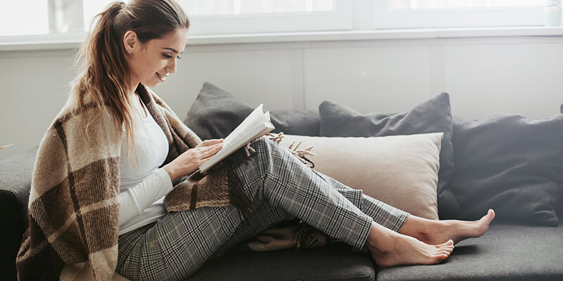 Woman wrapped in blanket reading book