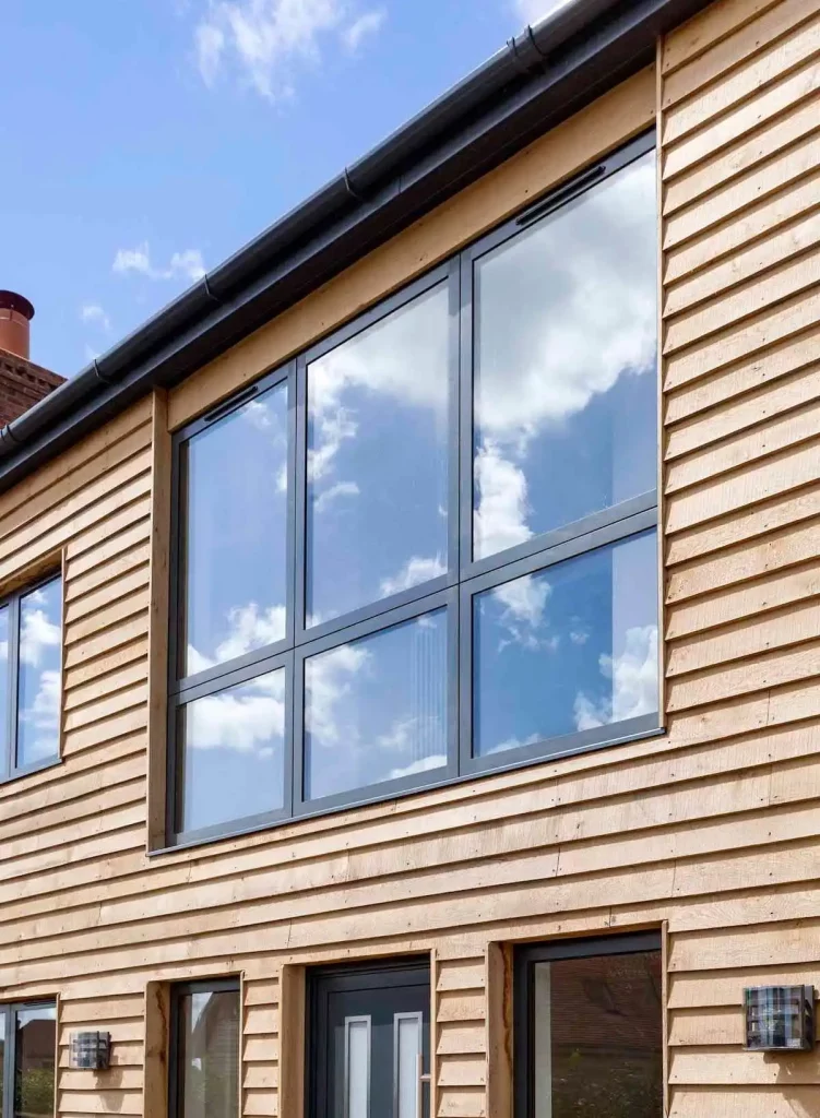 Large modern windows installed on a timber-clad house facade