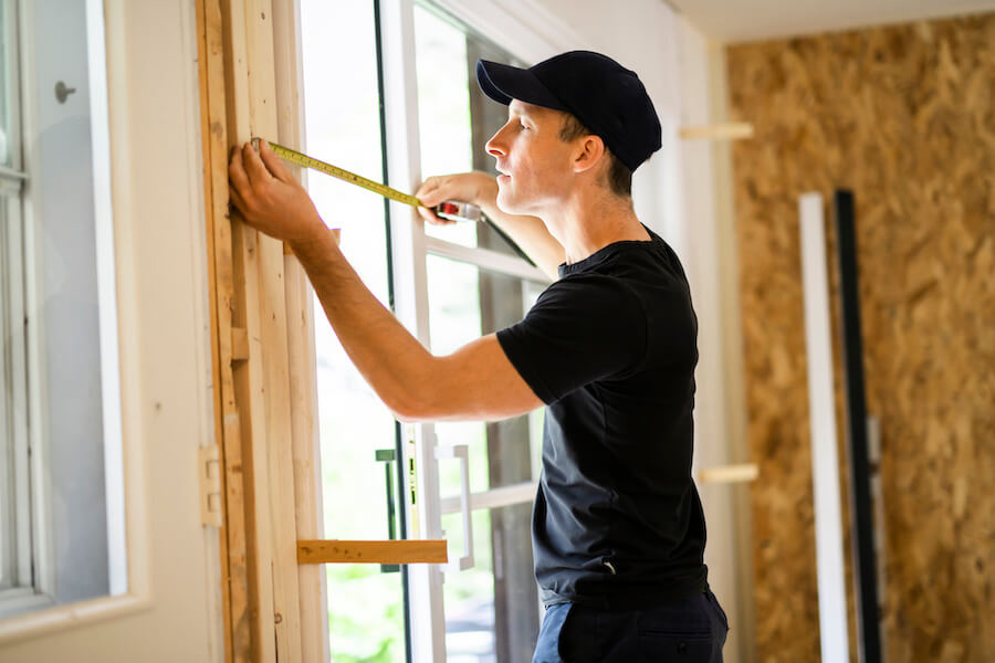 handsome young man installing Double Sliding Patio Door in a new house construction site