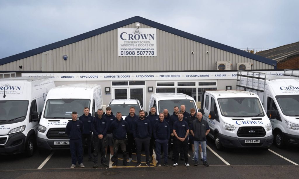 Crown Conservatories, Windows and Doors Ltd team posing with company vans outside their headquarters.